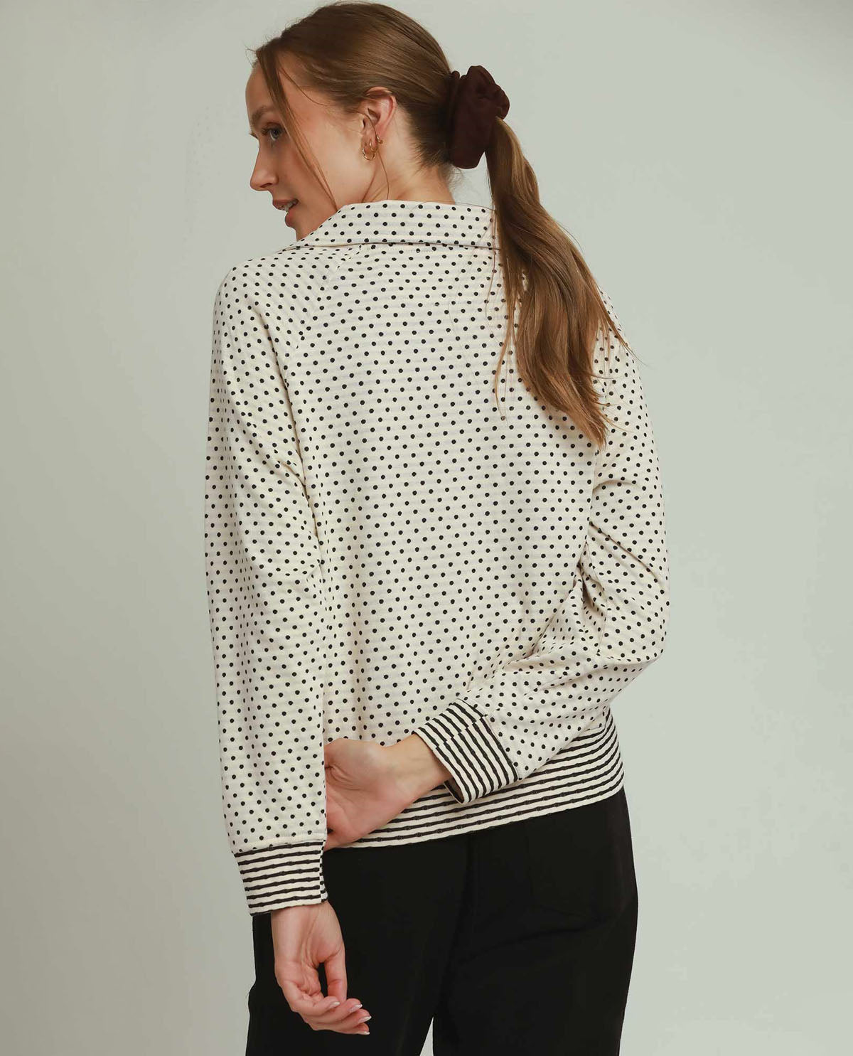 Woman wearing a polka dot blouse with a plain background