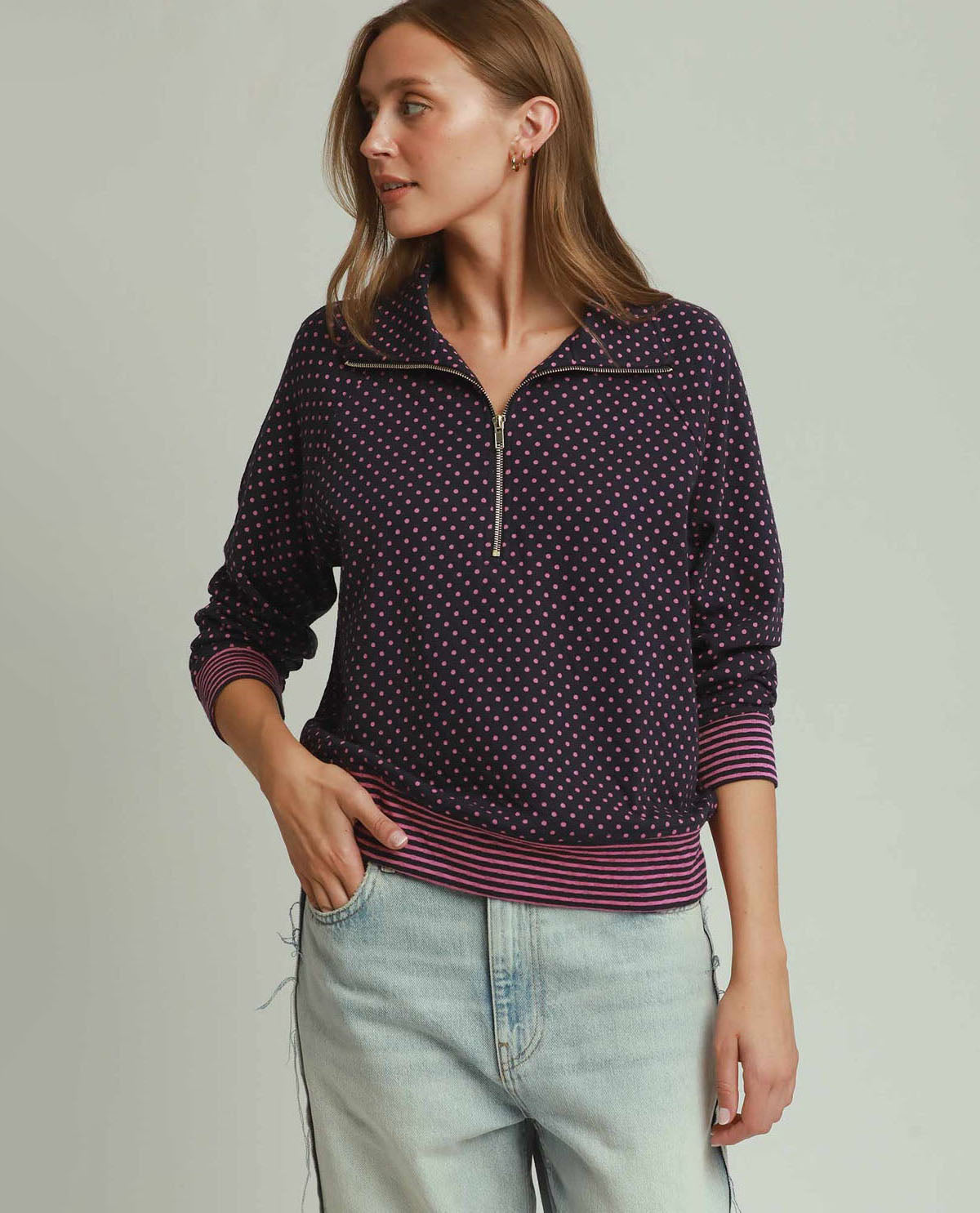 Woman wearing a patterned purple pullover with a neutral background