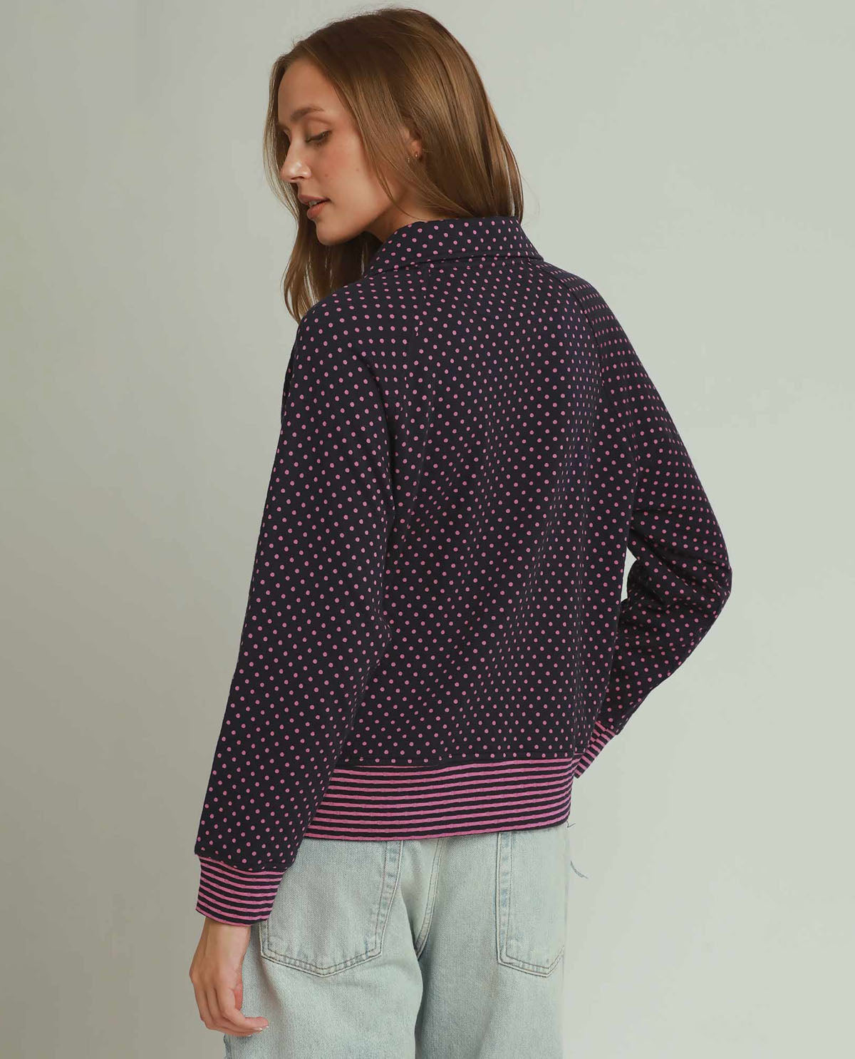 Woman wearing a dark patterned shirt with a light background