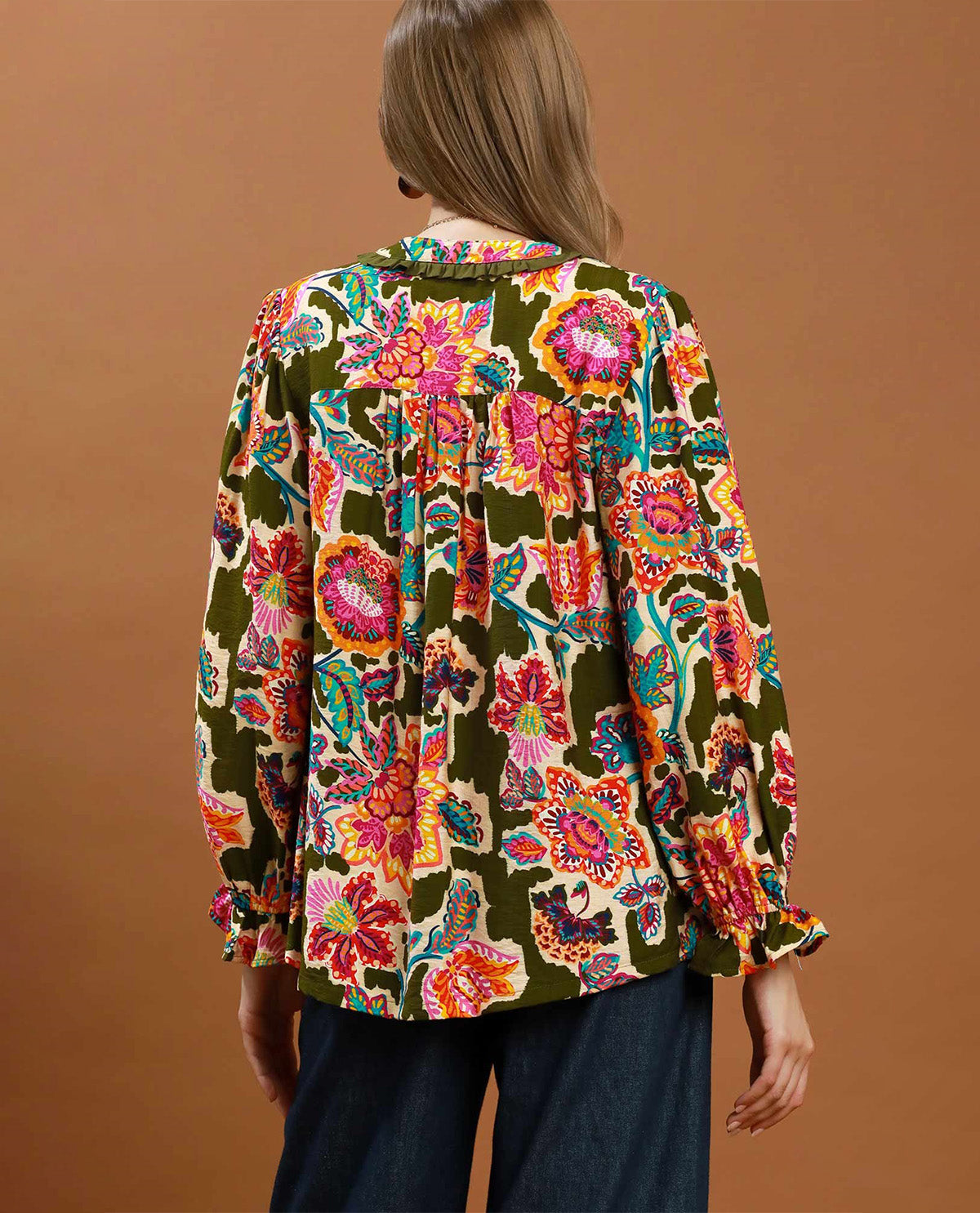 Woman wearing a colorful floral blouse against a brown background