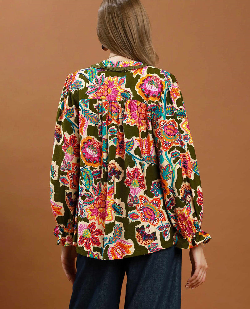 Woman wearing a colorful floral blouse against a brown background
