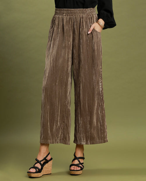 Brown wide-leg pants worn by a person on an olive green background