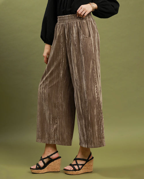 Person wearing brown pleated pants on a green background