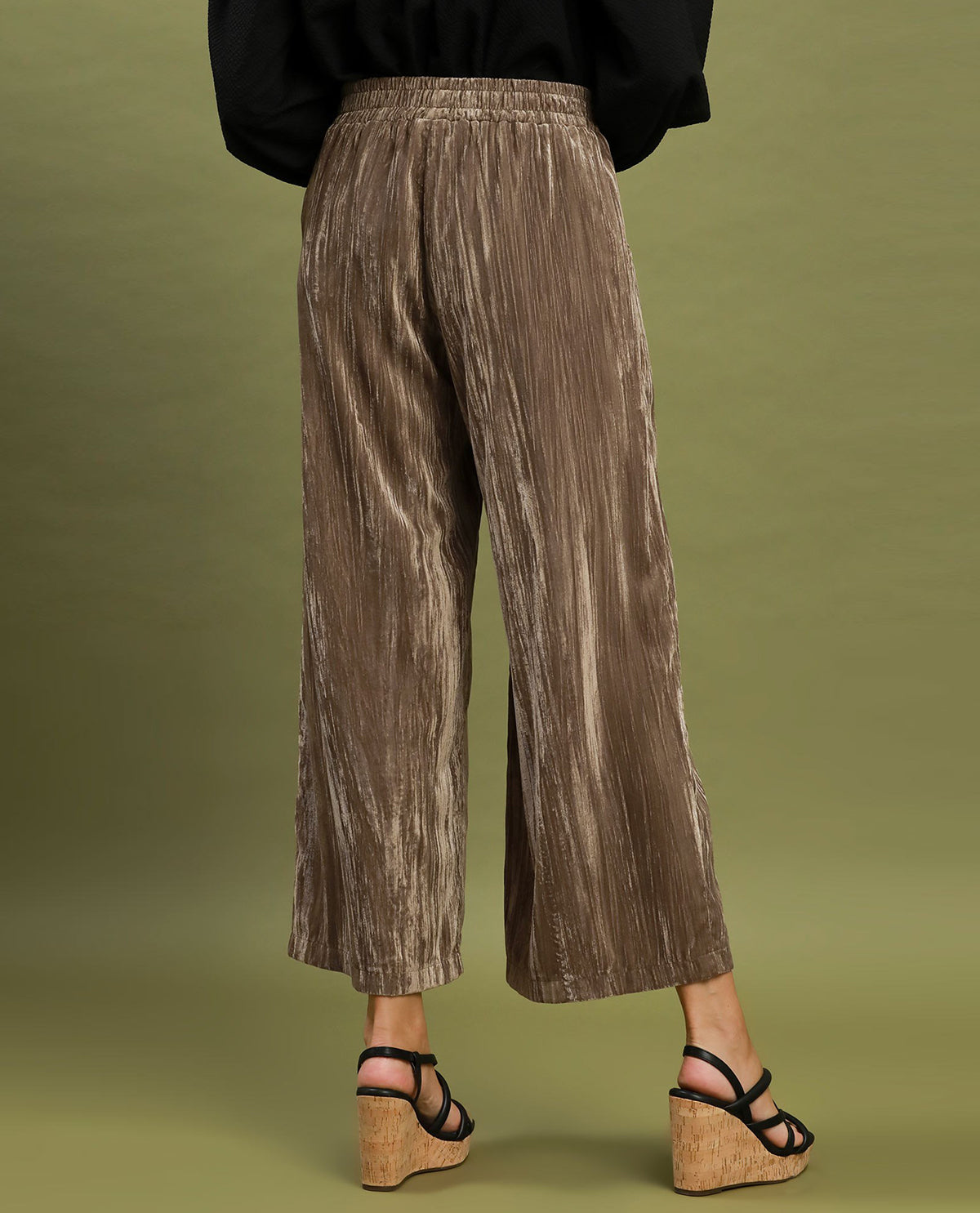 Person wearing brown pleated pants on a green background