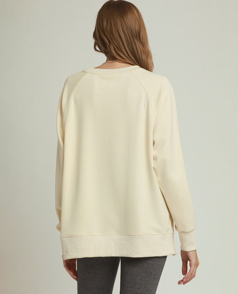 Person wearing a cream-colored sweatshirt on a plain background
