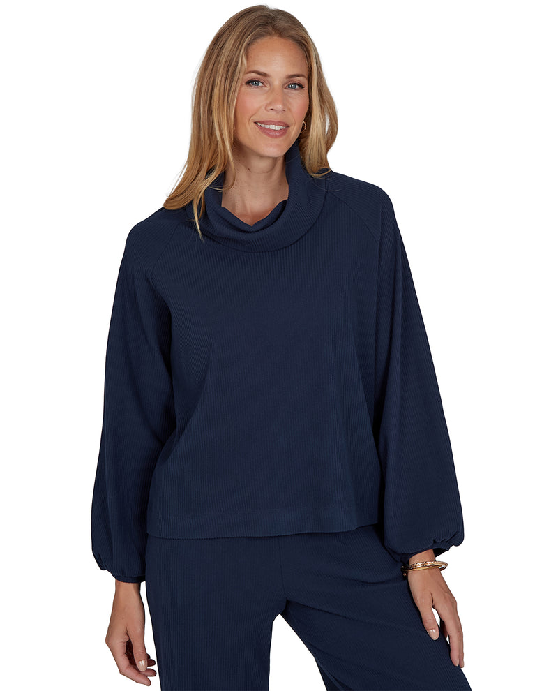 Woman wearing a navy blue cowl-neck sweater on a white background