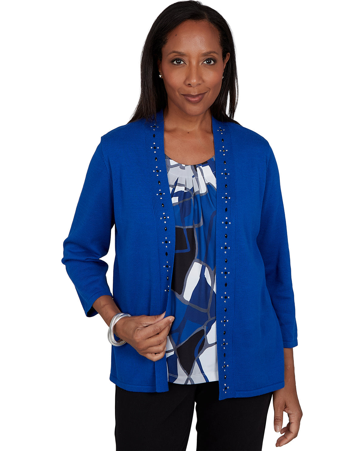 A woman modeling a bright blue open-front cardigan with decorative silver-tone studs down the front, worn over a black, white, and blue patterned top.