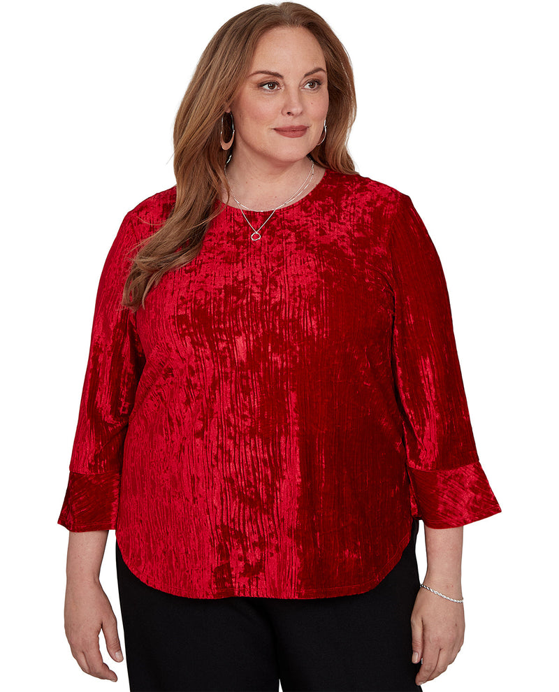 A woman modeling a red sequined long-sleeve top with three-quarter sleeves and black pants against a plain white background.