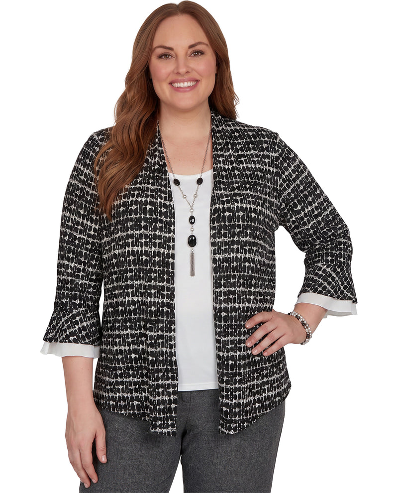 A woman modeling a black and white textured tweed open-front cardigan with three-quarter bell sleeves, worn over a white top and gray pants against a plain white background.