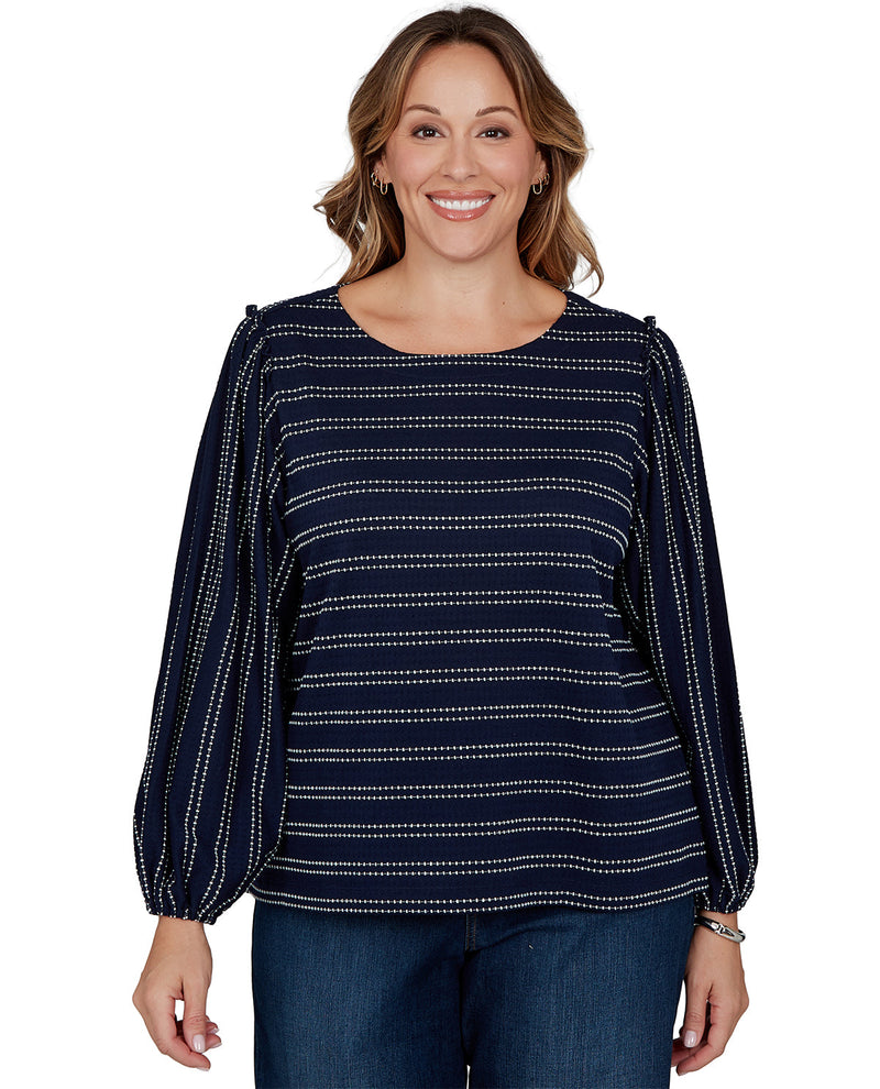 Woman wearing a navy blue top with white patterns on a white background