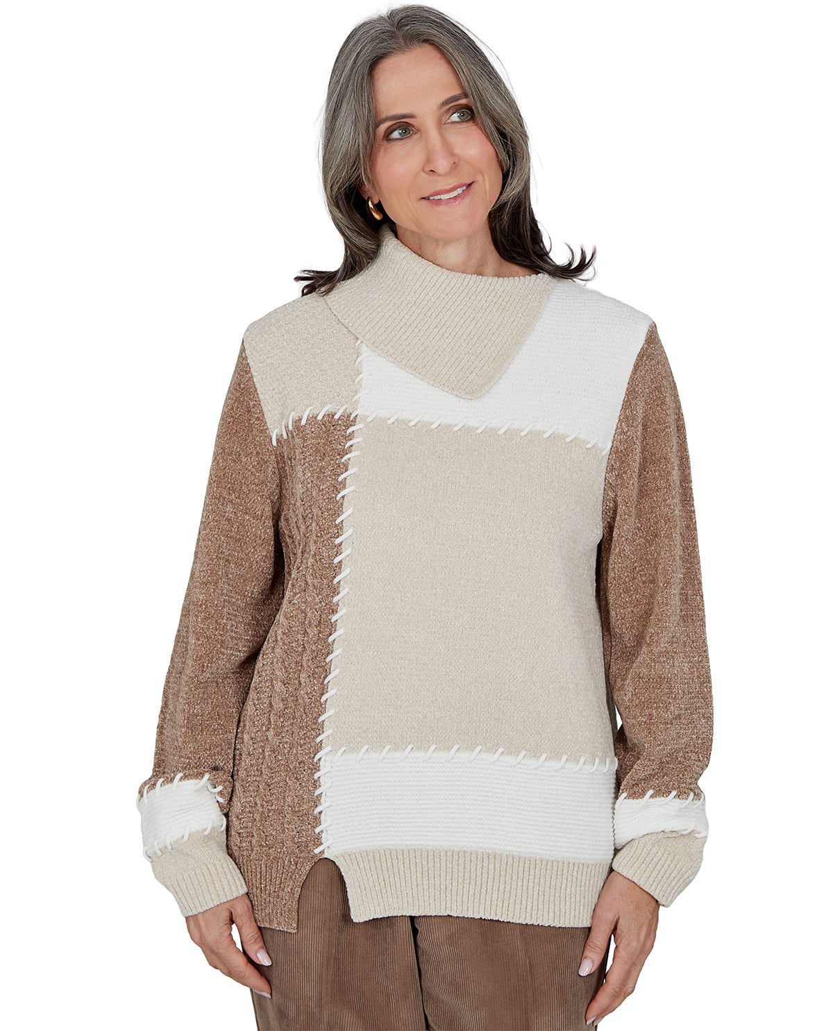 A woman wearing a color-block knit sweater with a high mock neck, brown sleeves and side panels, and cream panels with textured zigzag seams, shown against a plain white background.