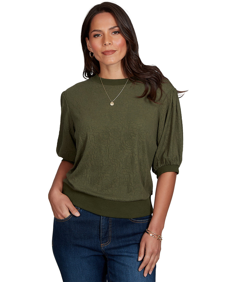 Woman wearing an olive green sweater and blue jeans on a white background