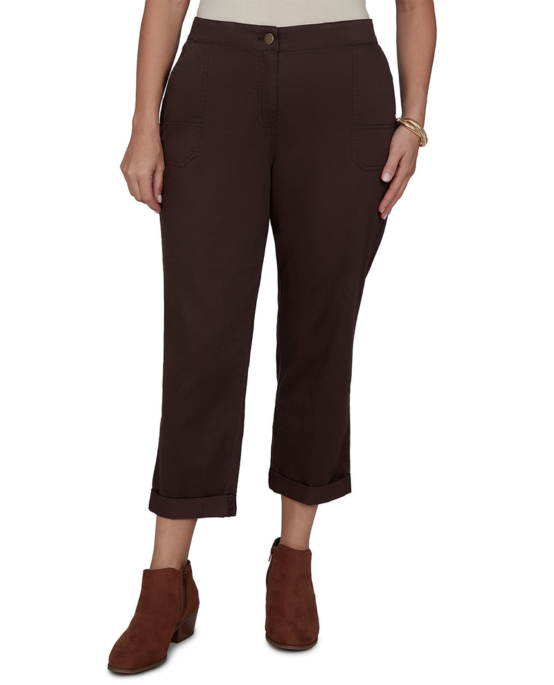 A model wearing dark brown cropped pants with rolled cuffs and side pockets, paired with brown ankle boots against a plain white background.