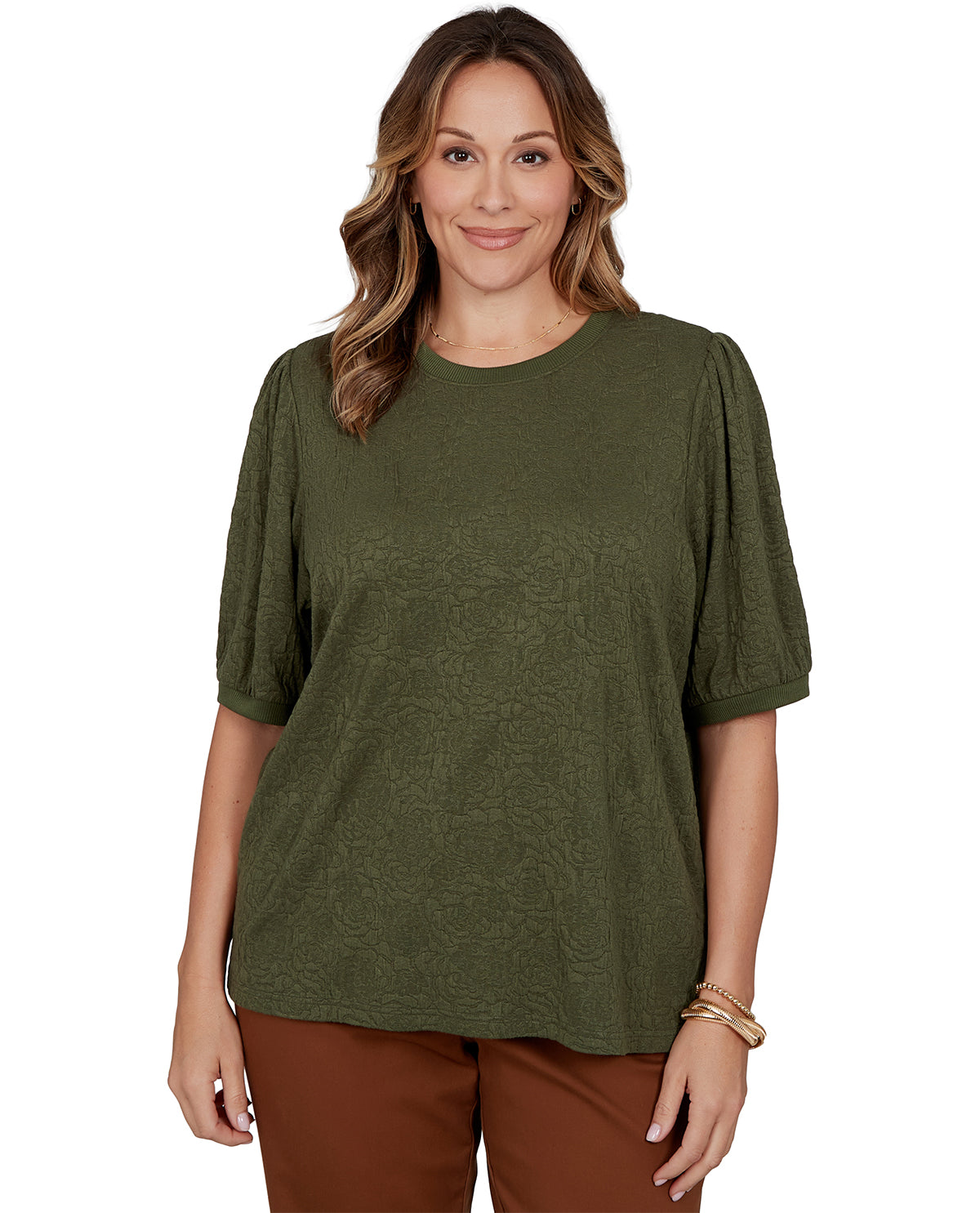 Woman wearing an olive green top and brown pants on a white background