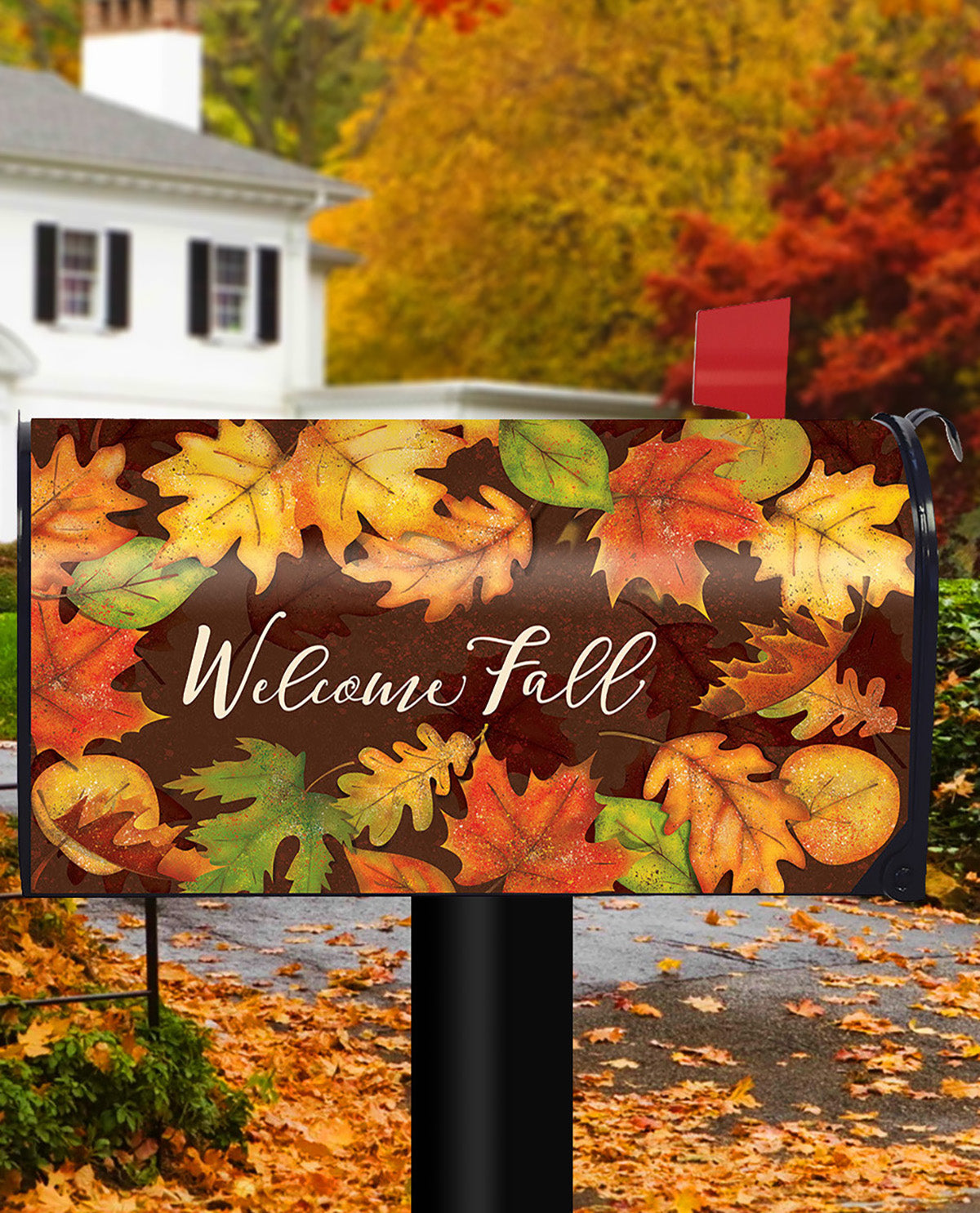A decorative mailbox cover featuring a fall leaf pattern and the words 'Welcome Fall' in white script, shown mounted on a black mailbox in a residential yard with autumn trees and fallen leaves in the background.
