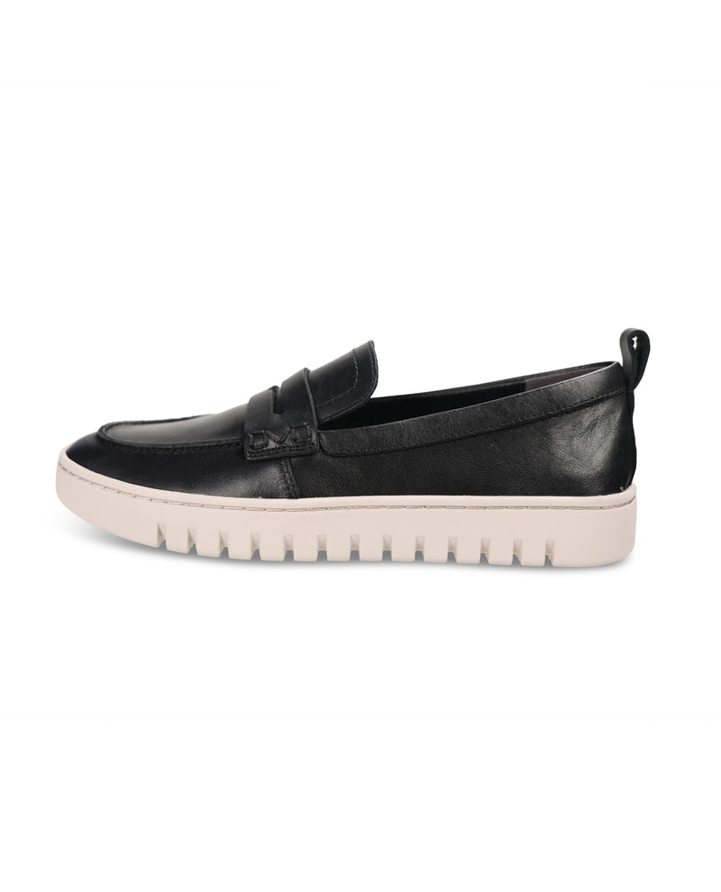 A black leather slip-on loafer with a textured off-white sole, shown in a side profile view against a plain white background.