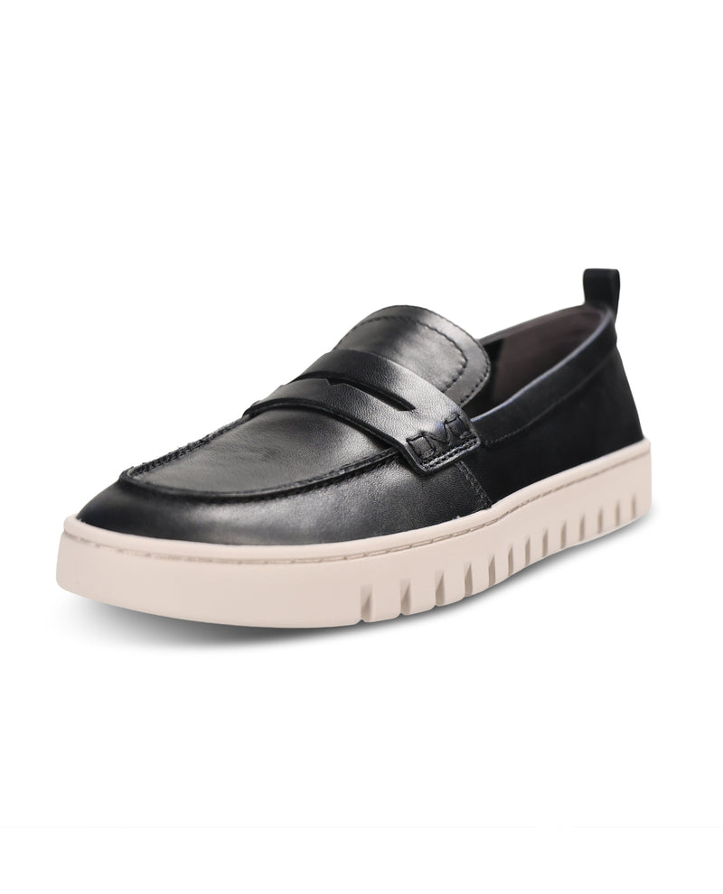 A black leather slip-on loafer with a decorative strap and a chunky, textured off-white platform sole, shown from a three-quarters angle on a white background.