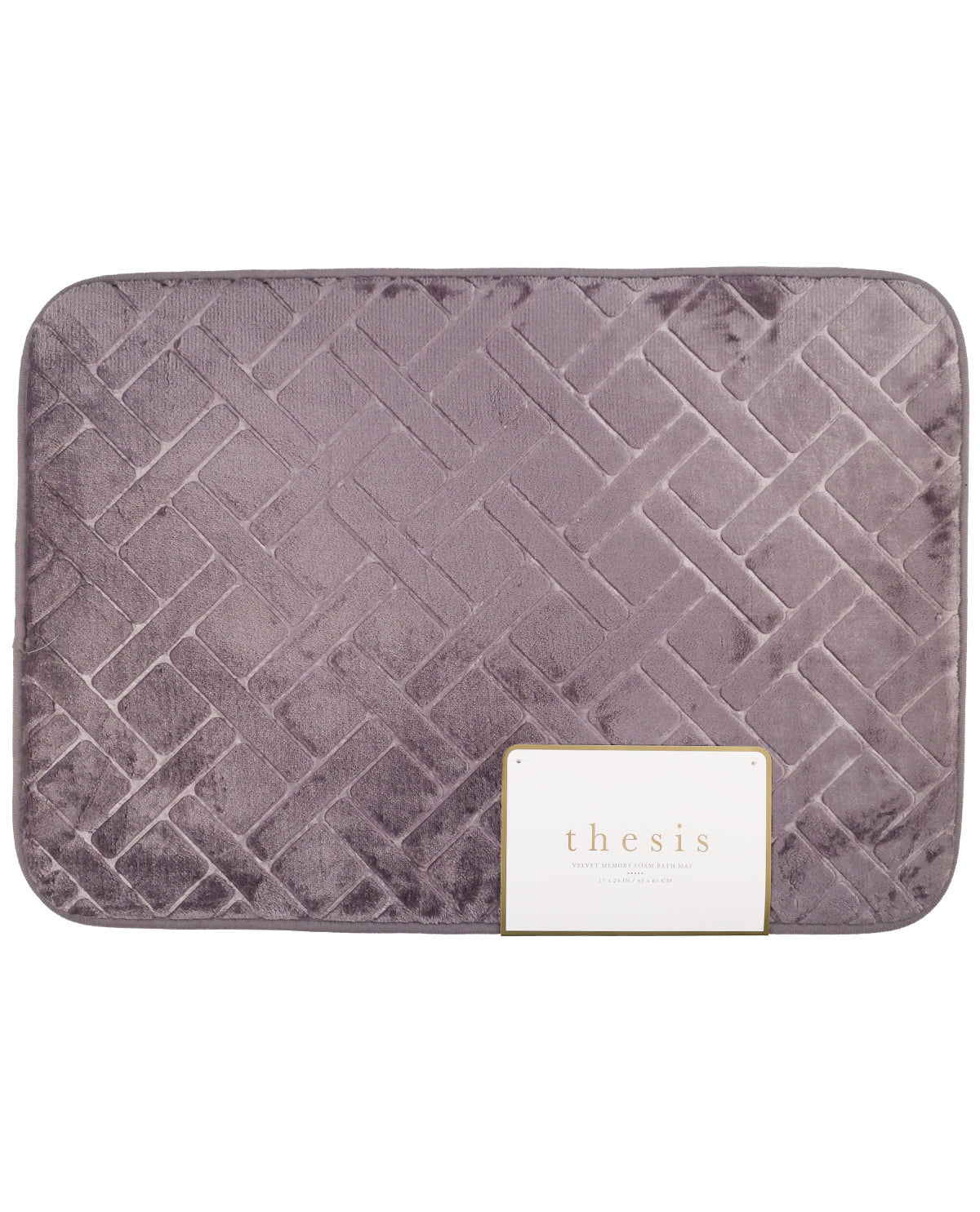 A square bath mat in a dusty purple velvet fabric with a raised basketweave pattern, featuring a white 'thesis' brand tag on the bottom right.