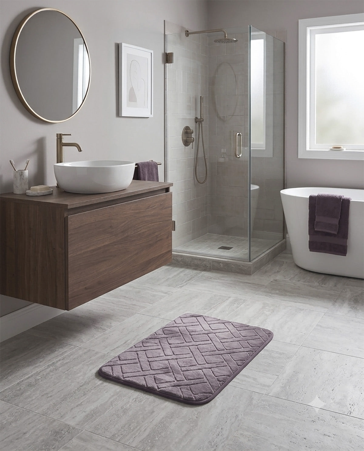 A modern bathroom scene with a purple textured bath mat on light gray stone-look floor tiles, a floating wooden vanity with a white vessel sink, a glass shower enclosure, and a white freestanding tub with a dark purple towel.