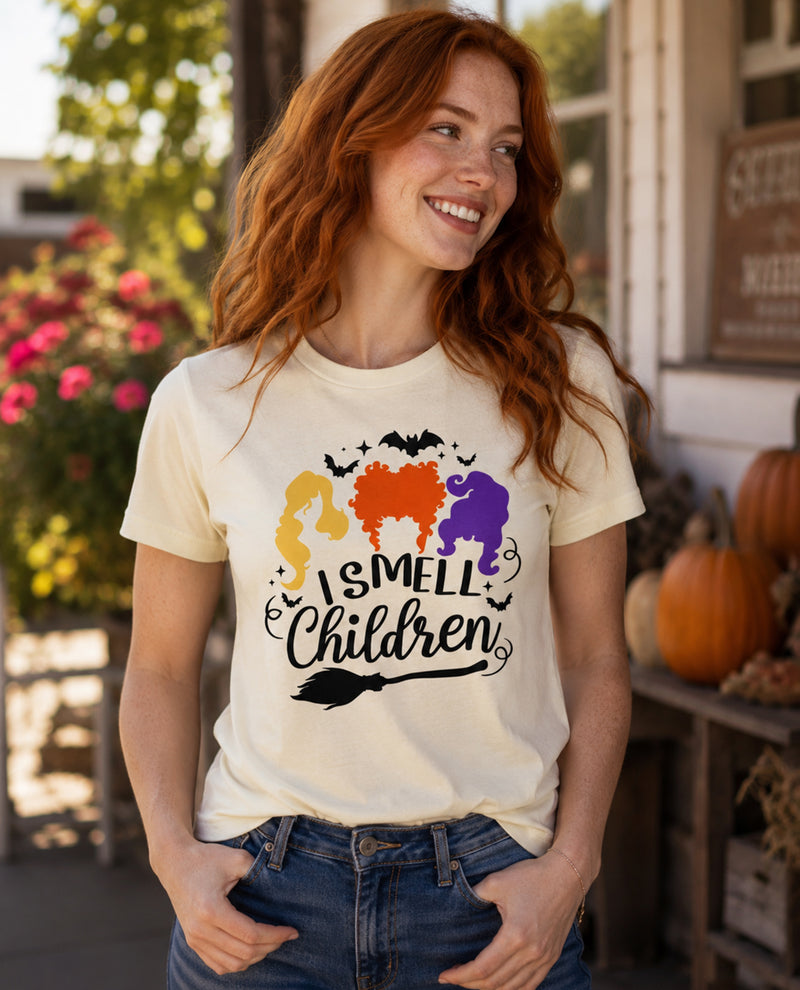Woman wearing a t-shirt with 'I Smell Children' graphic in an outdoor setting with pumpkins and flowers.