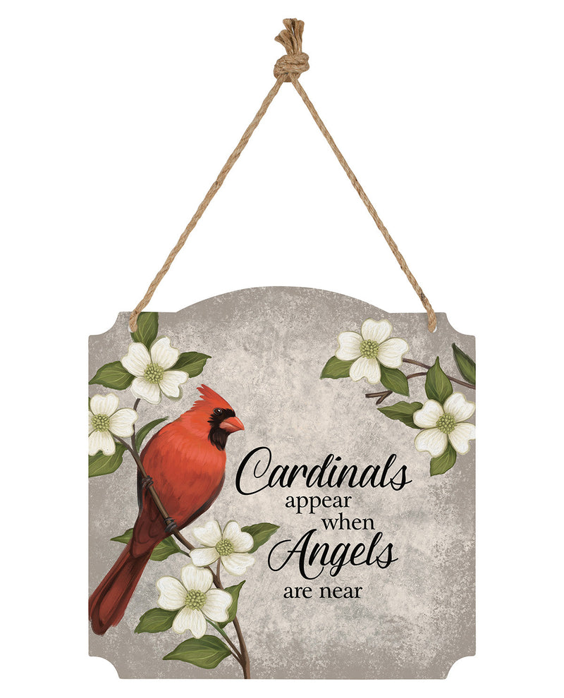 A hanging decorative sign with a red cardinal perched among white flowers on a textured gray background, with the phrase “Cardinals appear when Angels are near” in black script. The sign is suspended by a rope hanger.