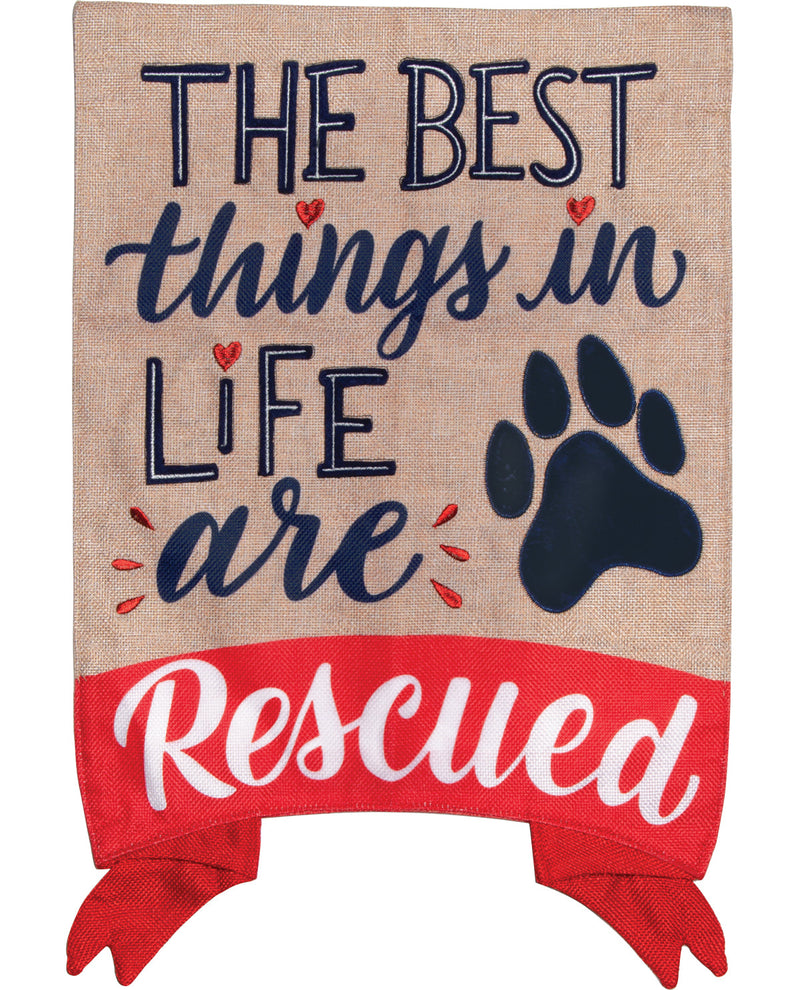 A rectangular burlap-style decorative sign or banner with the phrase “THE BEST things in LIFE are Rescued.” The top portion is tan burlap with navy lettering and small red heart and dash accents, while the bottom is a red band with white script reading “Rescued.