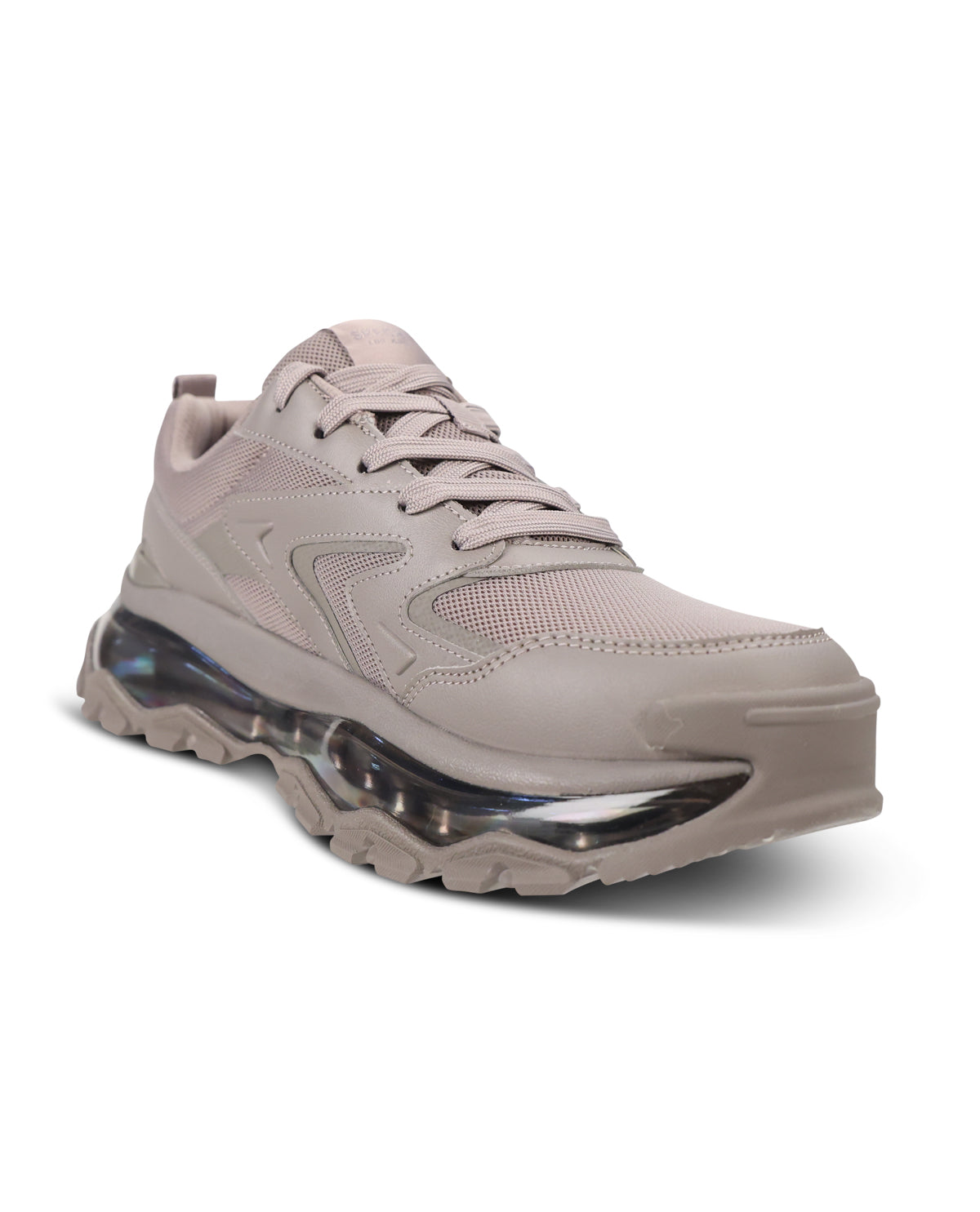 A single low-top athletic sneaker in a light taupe-beige colorway, featuring a chunky midsole with a visible transparent air cushion unit and a rugged treaded outsole, set against a plain white background.