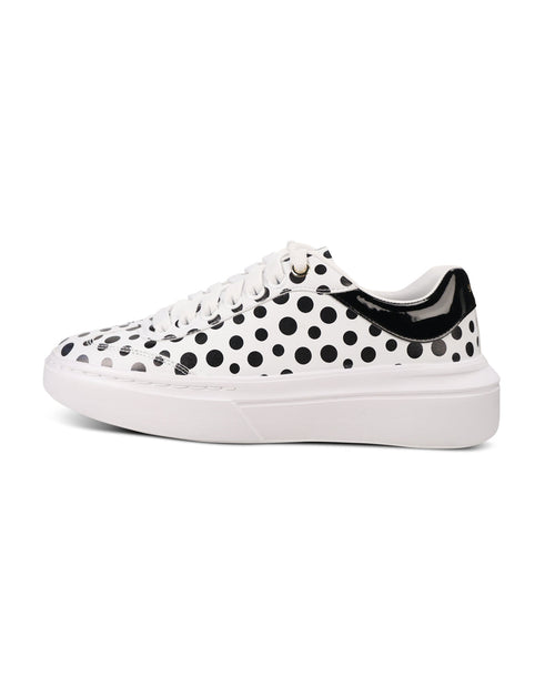 A white low-top sneaker featuring a black polka dot pattern across the upper, white laces, and a thick white platform sole with a black heel accent.
