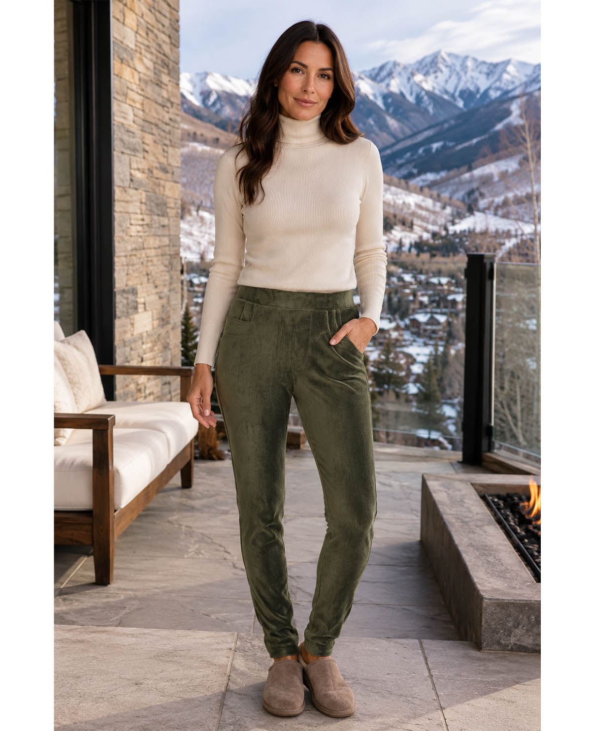 Woman standing on a patio with mountains in the background wearing a white turtleneck and green pants.