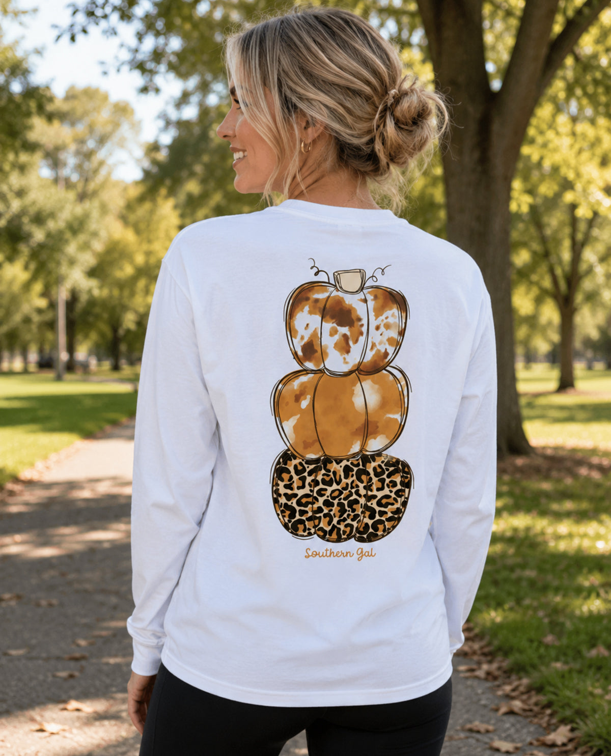 Woman wearing a white long-sleeve shirt with pumpkin design outdoors