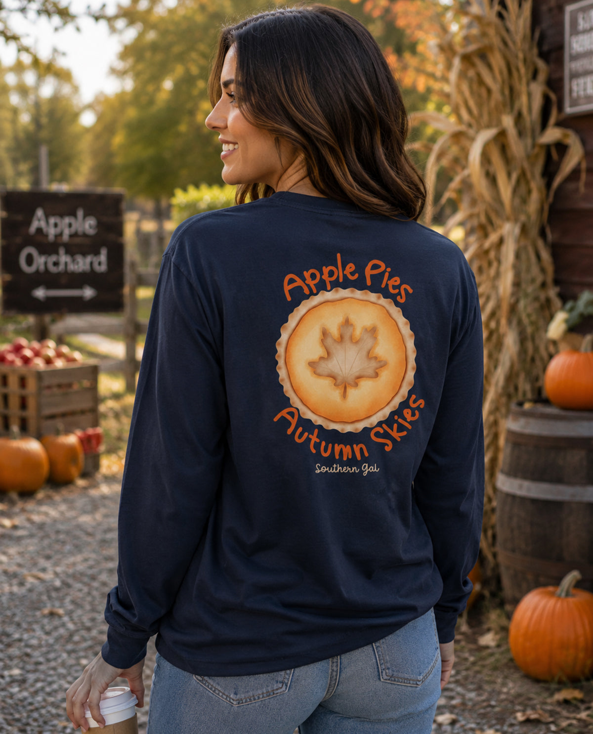 Woman wearing a navy blue long-sleeve shirt with a pumpkin patch design at an apple orchard.