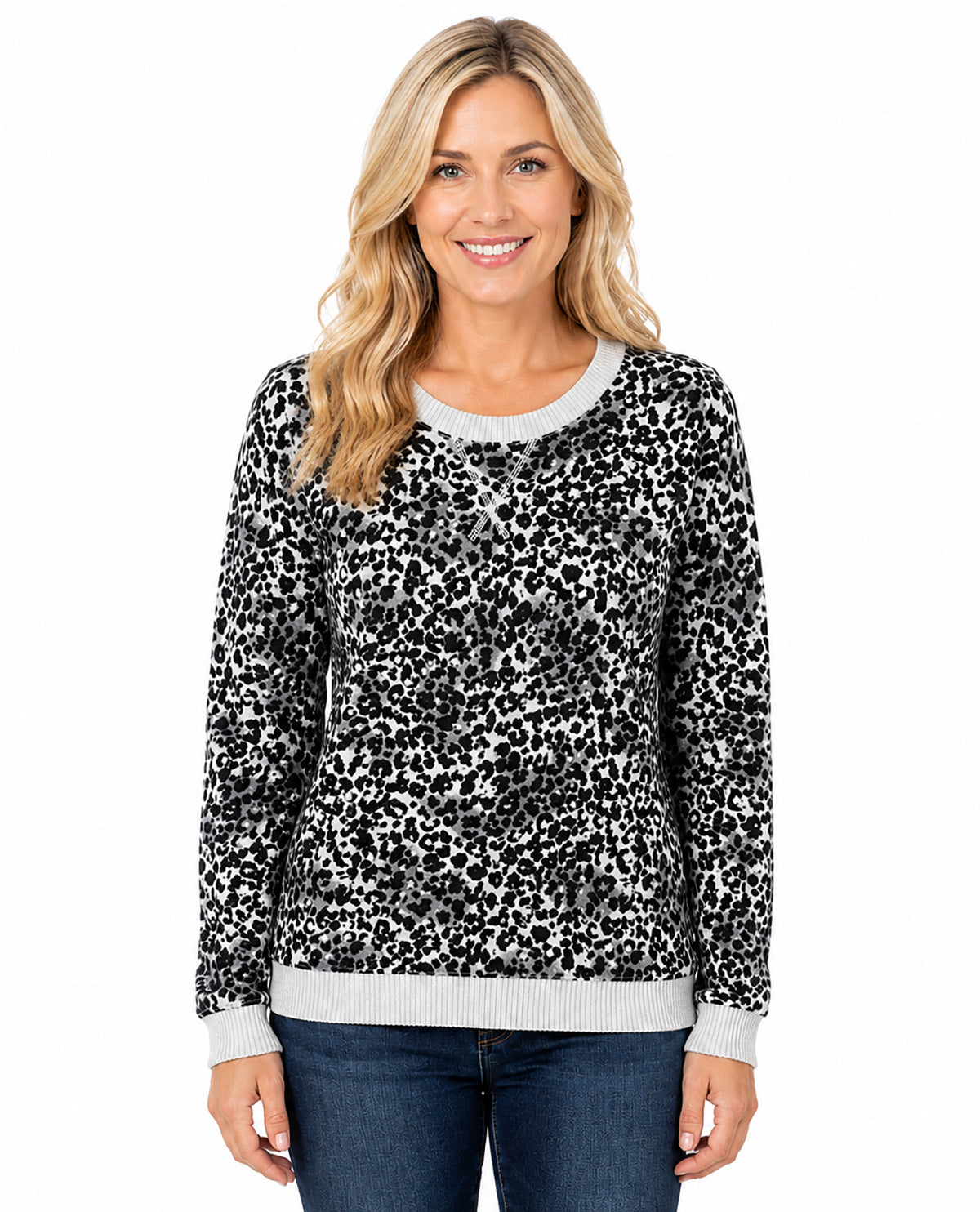 A woman modeling a black and white leopard print long-sleeve sweater with light gray ribbed trim on the crew neck, cuffs, and hem, paired with blue jeans against a plain white background.