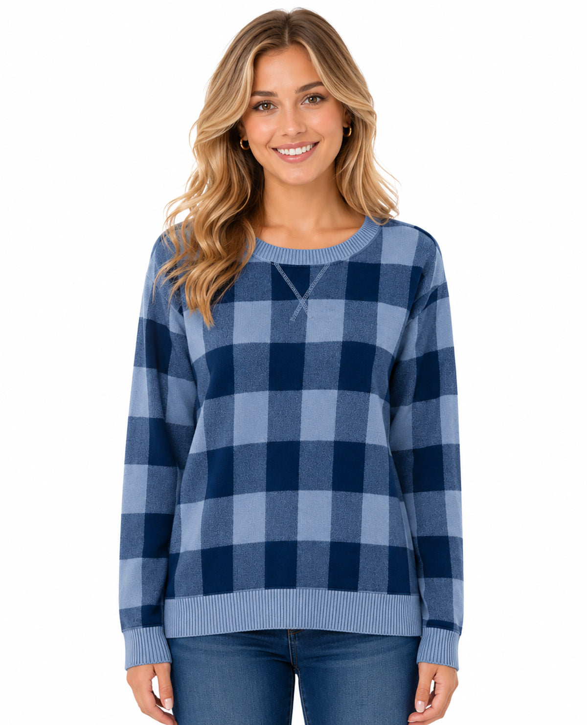 A woman wearing a blue and navy buffalo plaid crewneck sweater with ribbed cuffs and hem, paired with blue jeans, against a plain white background.