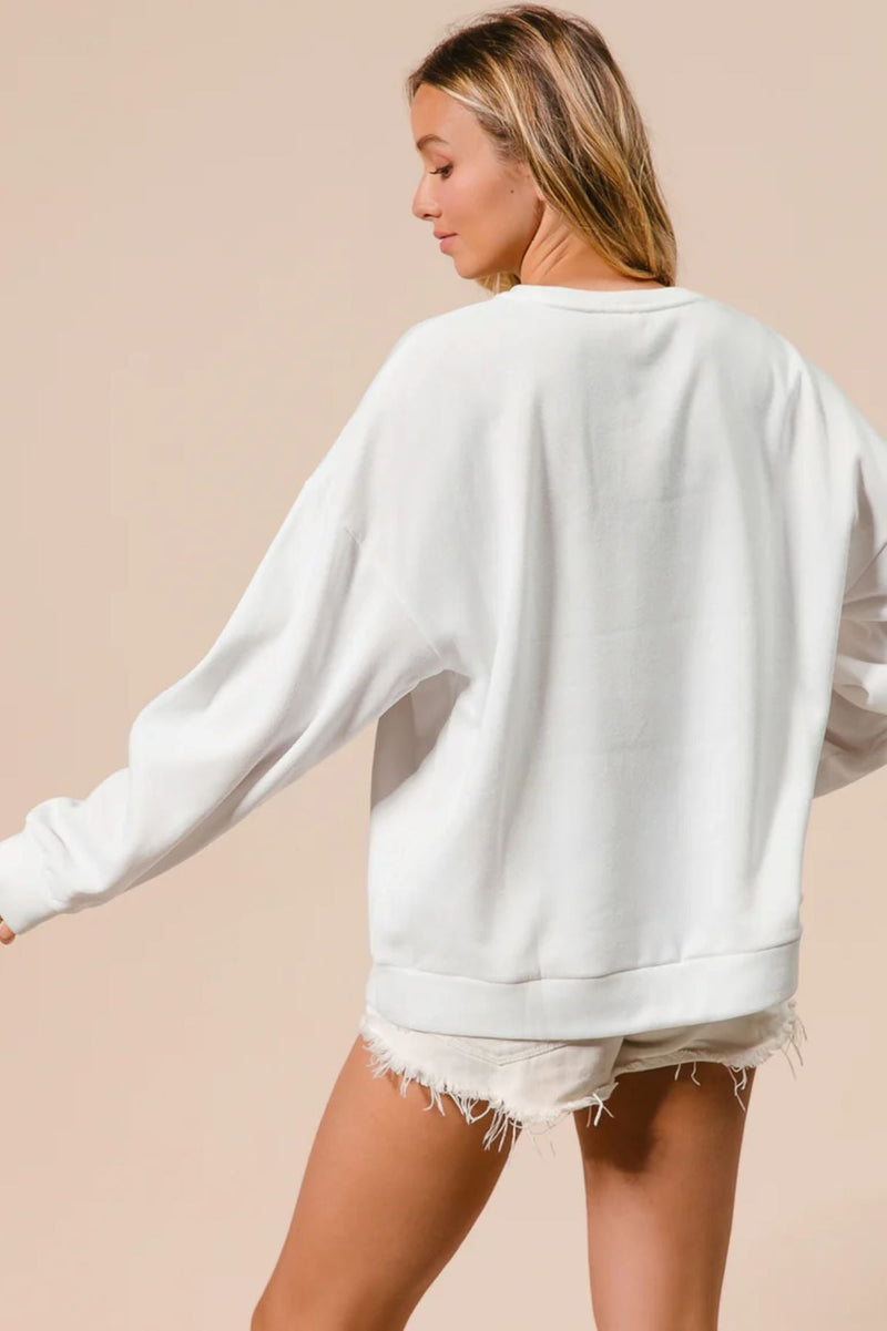Woman wearing a white sweatshirt and denim shorts on a beige background