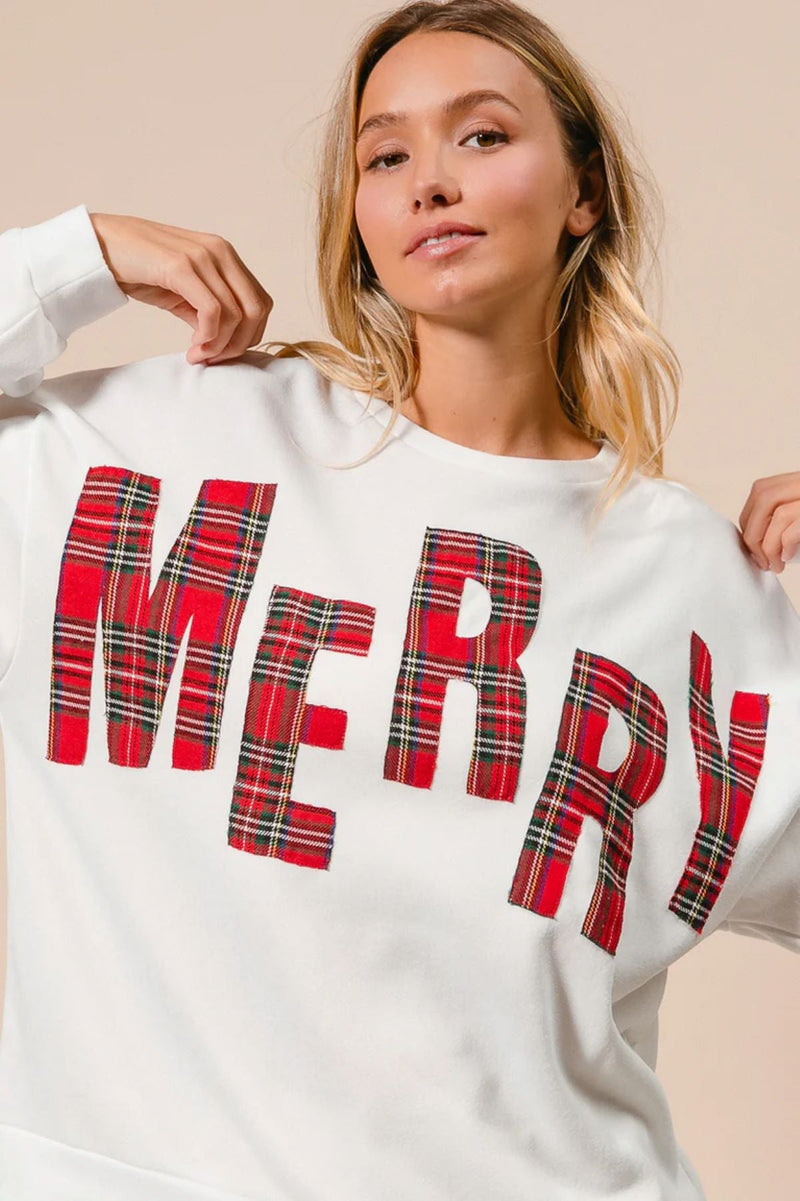 Person wearing a white sweatshirt with 'MERRY' in red plaid letters.