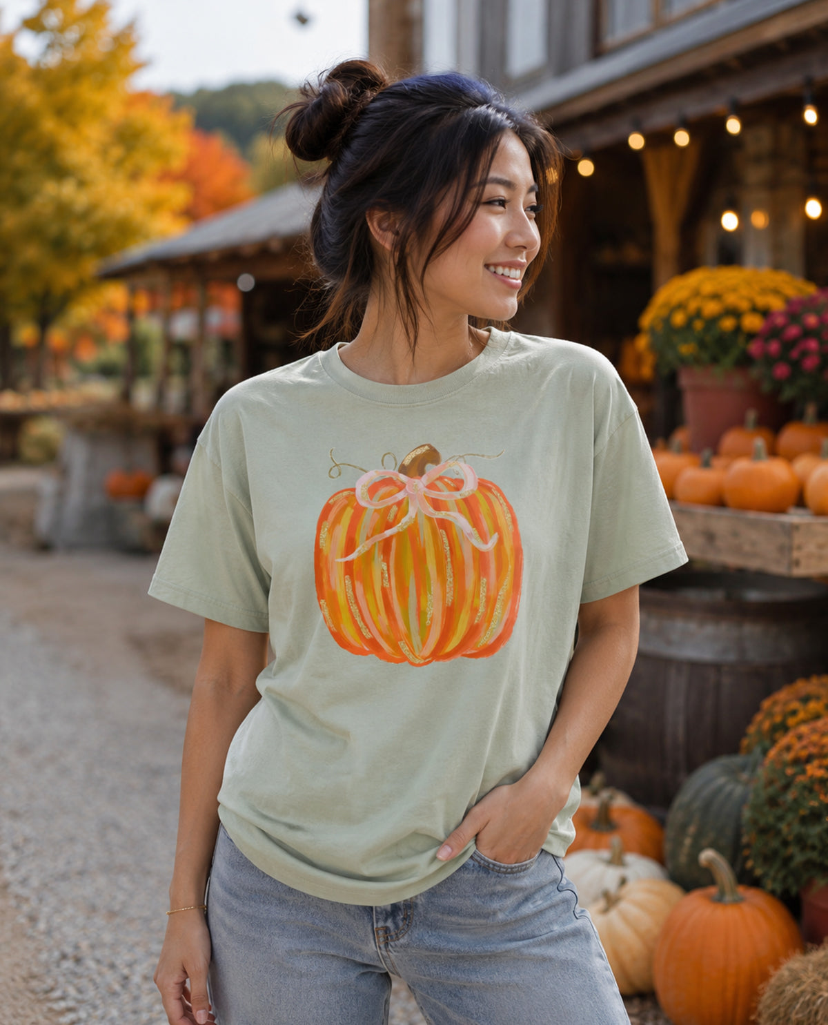 Woman wearing a t-shirt with a pumpkin design at an outdoor market.