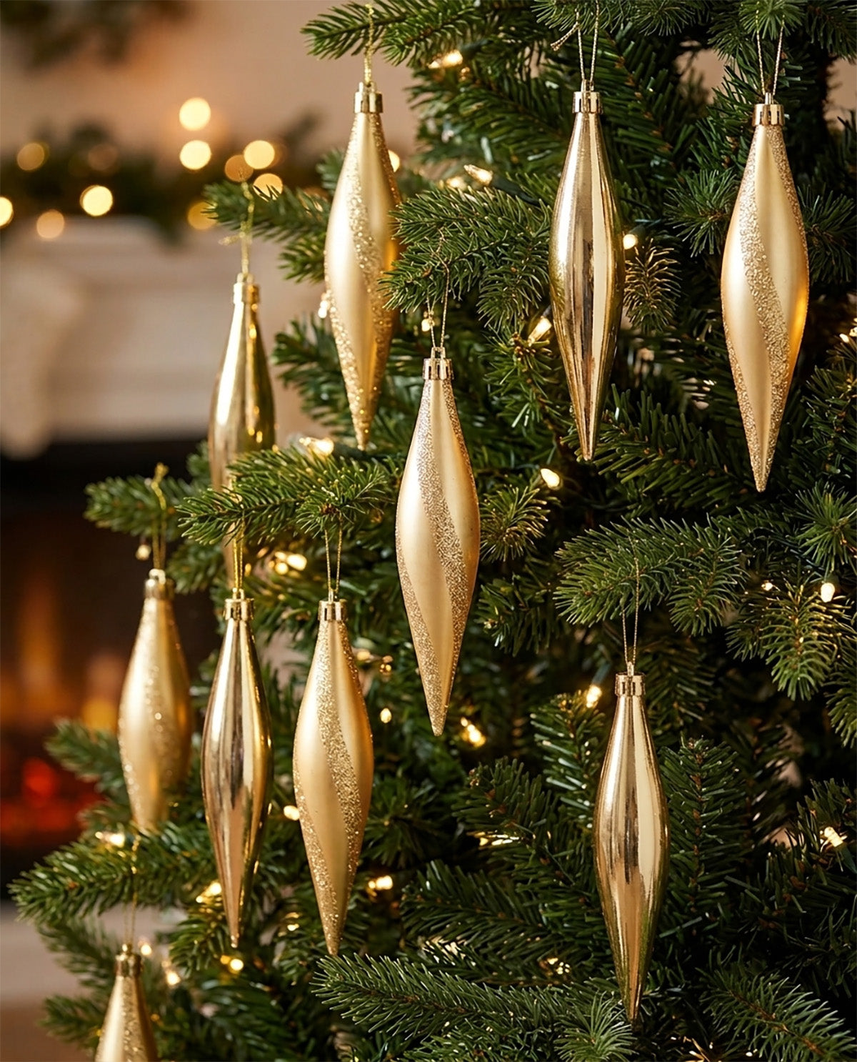 Gold metallic Christmas tree ornaments hanging on a green evergreen tree with warm string lights in a cozy indoor setting.