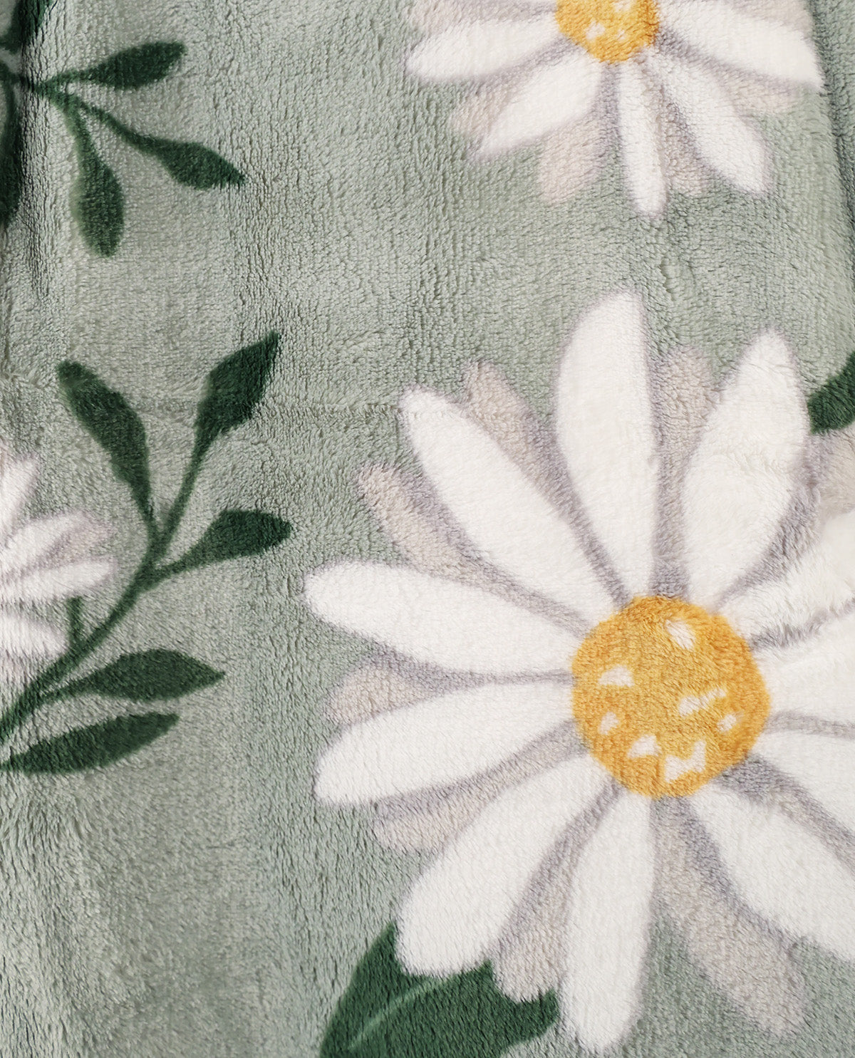 Close-up of a plush fleece blanket featuring a daisy floral pattern with white petals, yellow centers, and dark green leaves on a muted sage green background.