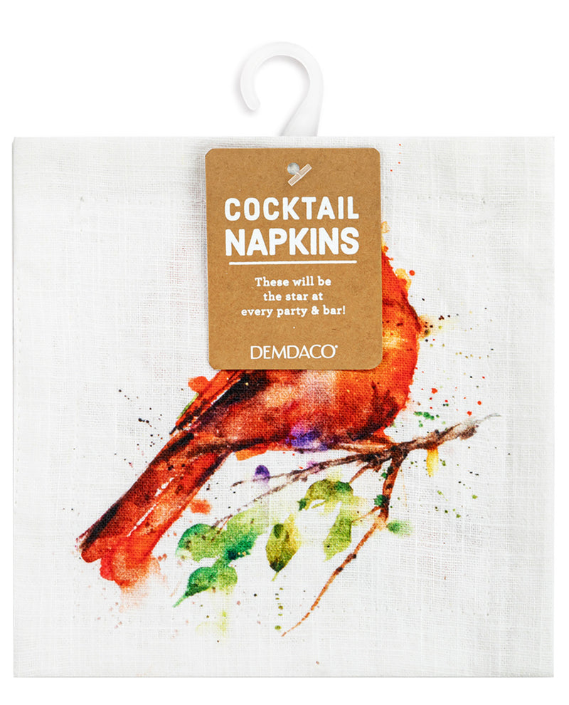 A white linen cocktail napkin featuring a watercolor-style red cardinal on a branch with green leaves, hanging from a white plastic hanger with a brown paper tag that reads 'COCKTAIL NAPKINS' and 'DEMDACO'.