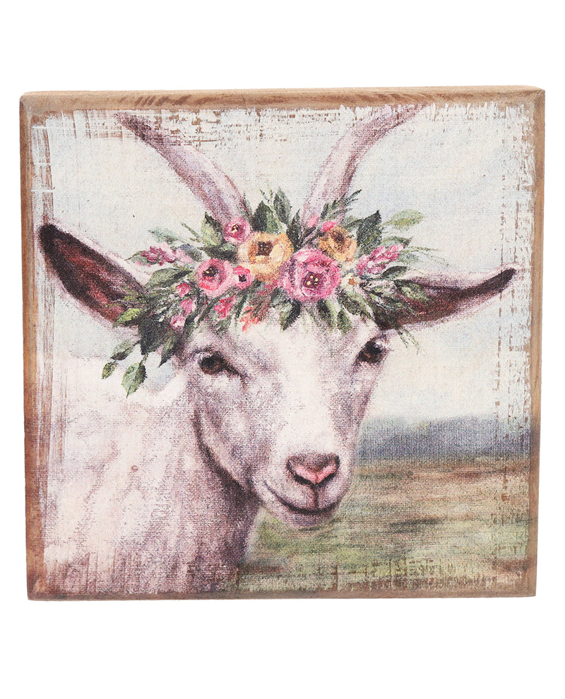 Decorative wall art of a goat with floral crown on a rustic wooden frame.