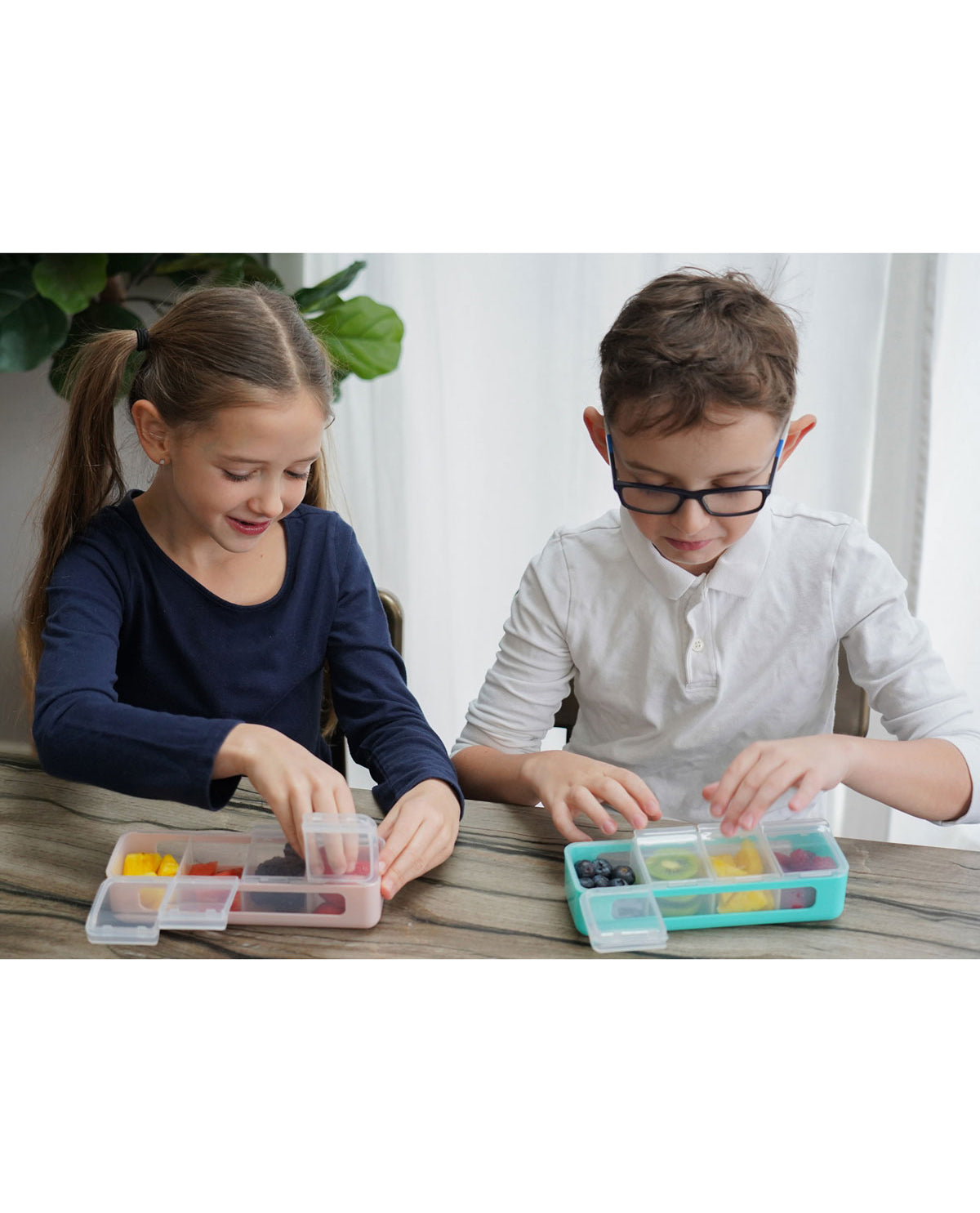 Two children playing with colorful compartments on a table.
