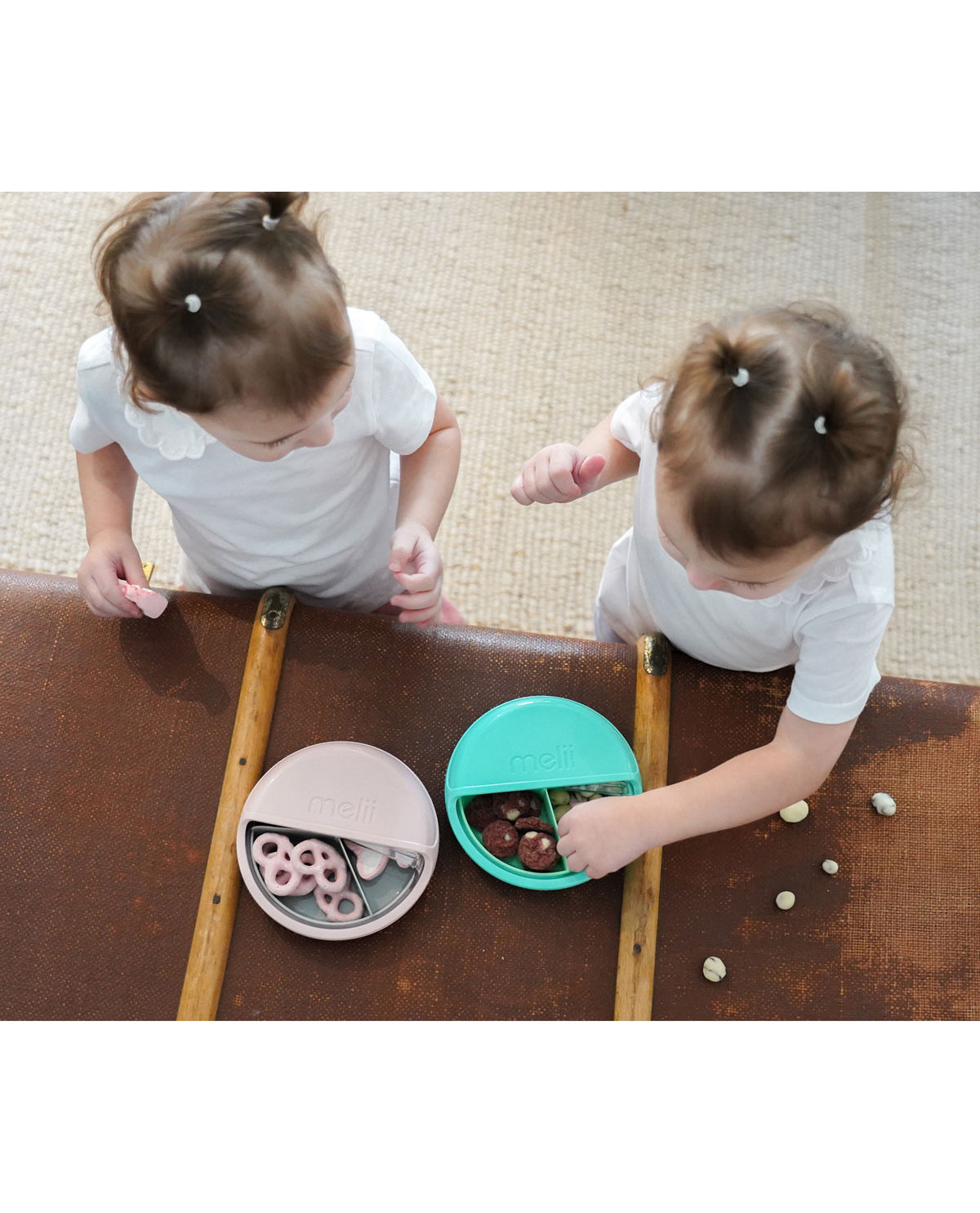 Two children playing with colorful bowls on a wooden table.