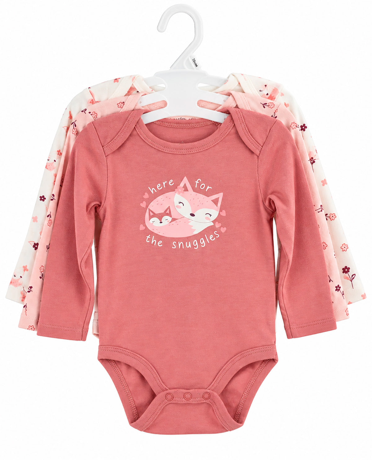 A set of three baby long-sleeve bodysuits on white hangers. The front bodysuit is dusty pink with a graphic of a sleeping fox and the text 'here for the snuggles'.