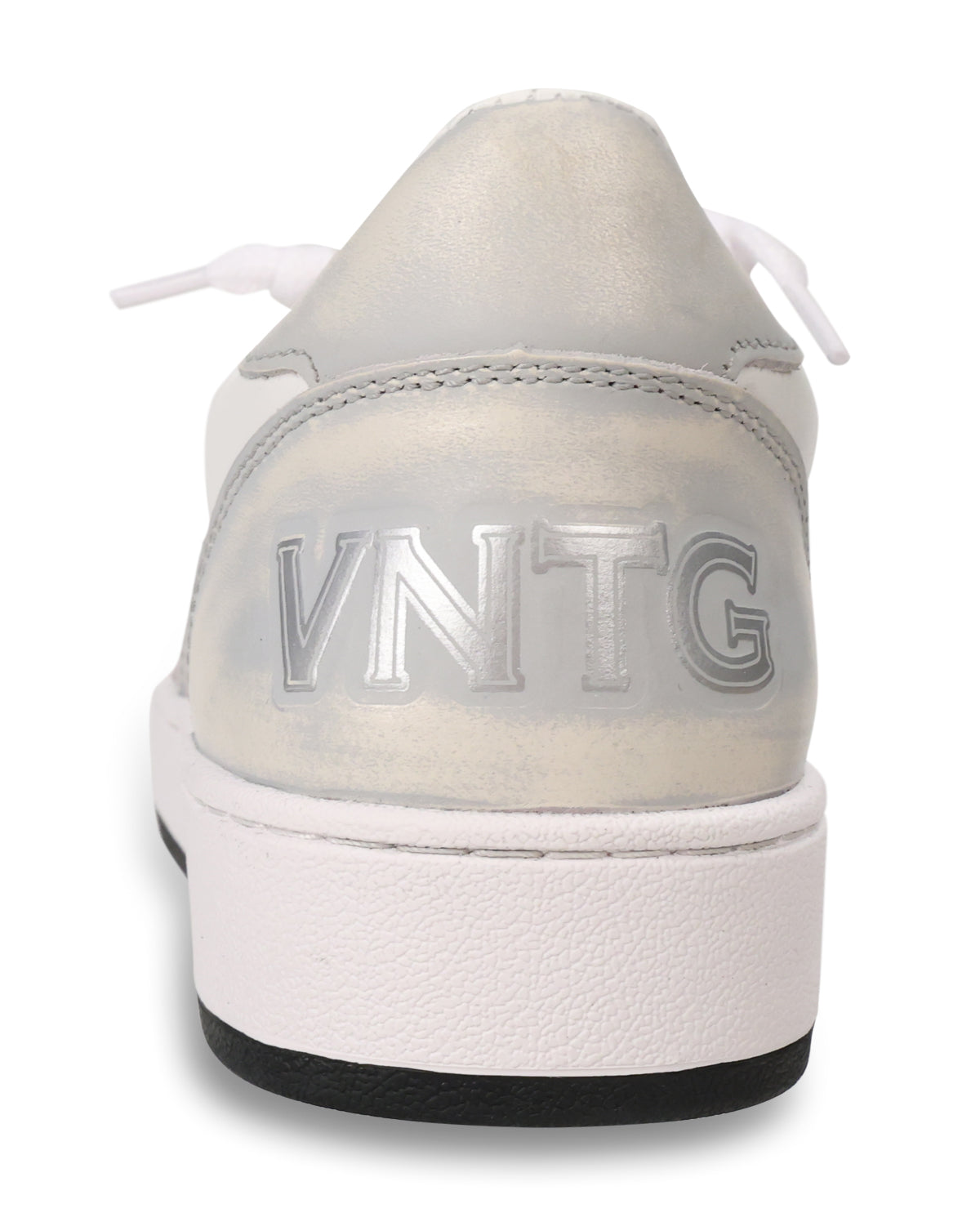 A close-up rear view of a low-top sneaker in metallic silver and white, featuring the embossed brand name 'VNTG' on the heel and a thick white platform sole with a black outsole.