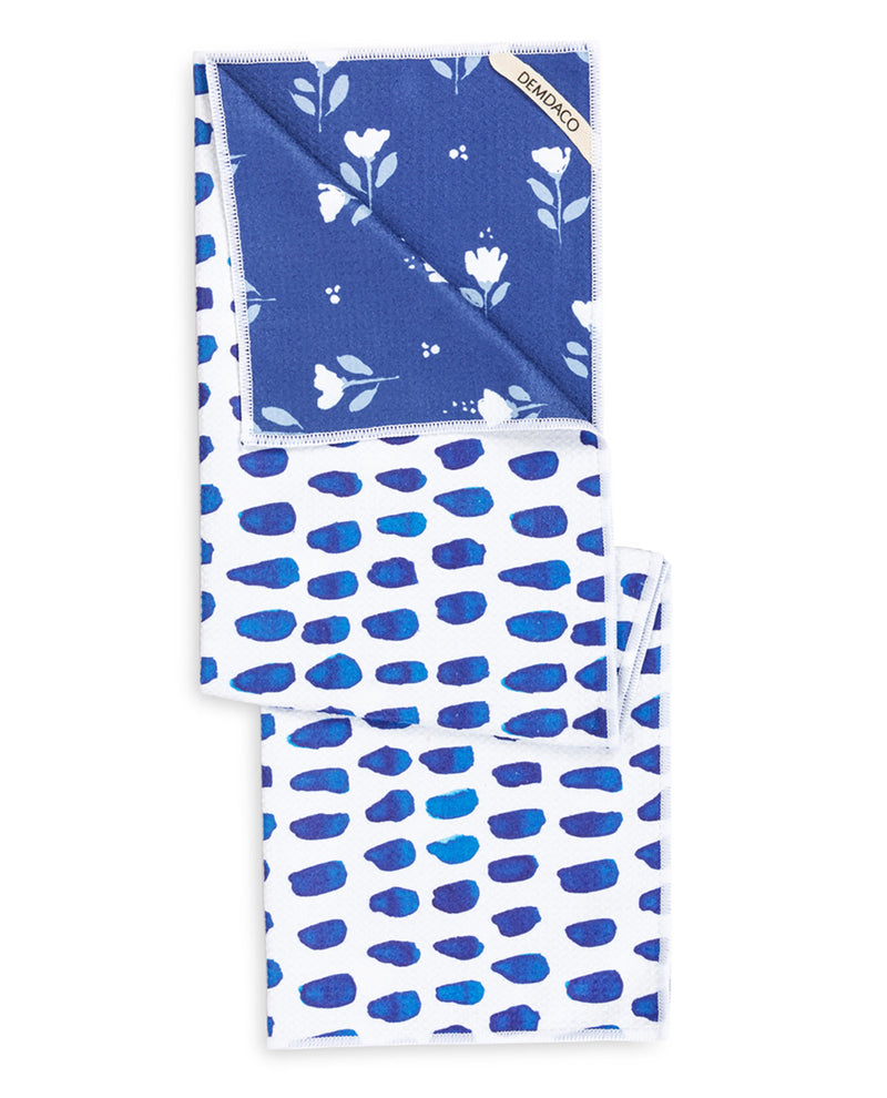 A folded bamboo cloth napkin with a blue and white floral pattern on one side and a blue abstract leaf pattern on the other, displayed on a clean white background.