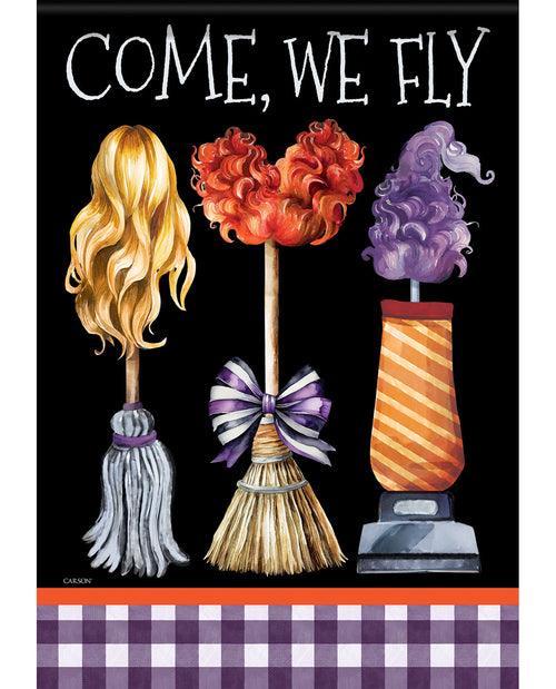 A decorative Halloween-style sign or print with the words “COME, WE FLY” at the top on a black background. Below, three whimsical broom-like figures are shown: one with long blonde hair, one with orange flower-like tops and a purple ribbon, and one with purple flower-like tops on an orange striped base.