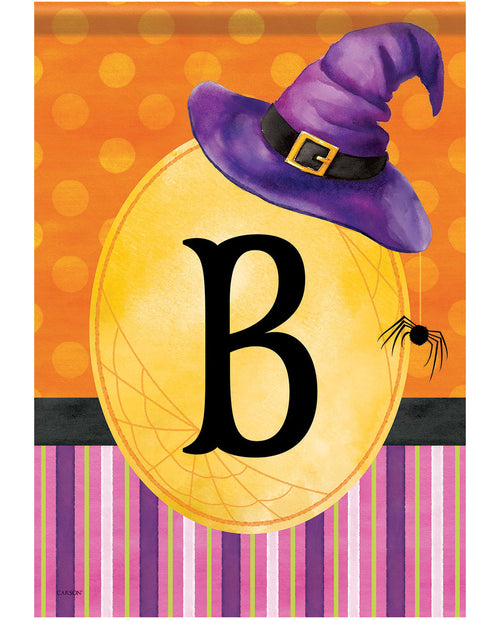 Halloween-themed decorative sign or print featuring a large yellow oval with a black letter B, a purple witch hat with a gold buckle, orange polka-dot background, spider detail, and purple striped bottom border.