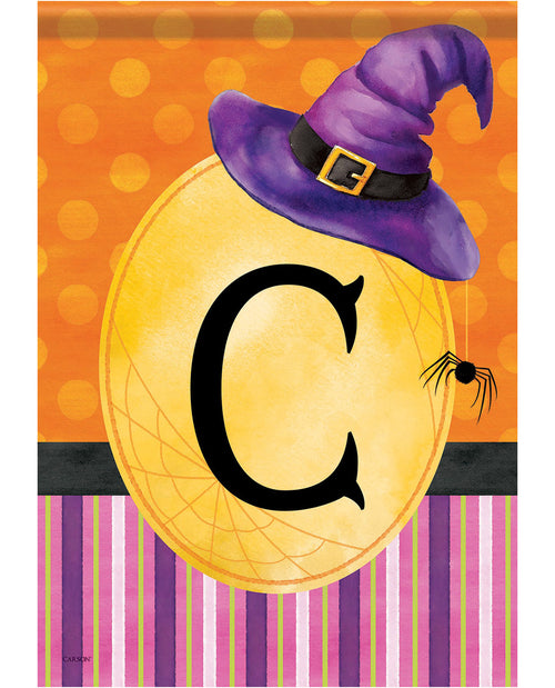 Halloween-themed decorative print featuring a large yellow circle with a black letter C, topped with a purple witch hat, on an orange polka-dot background with purple and pink striped bands and a small spider detail.