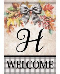 A decorative autumn-themed welcome sign featuring a large black script letter H in the center, surrounded by colorful fall leaves, acorns, and a gray-and-white plaid bow. The bottom section has a black-and-white plaid band with the word WELCOME in black capital letters.