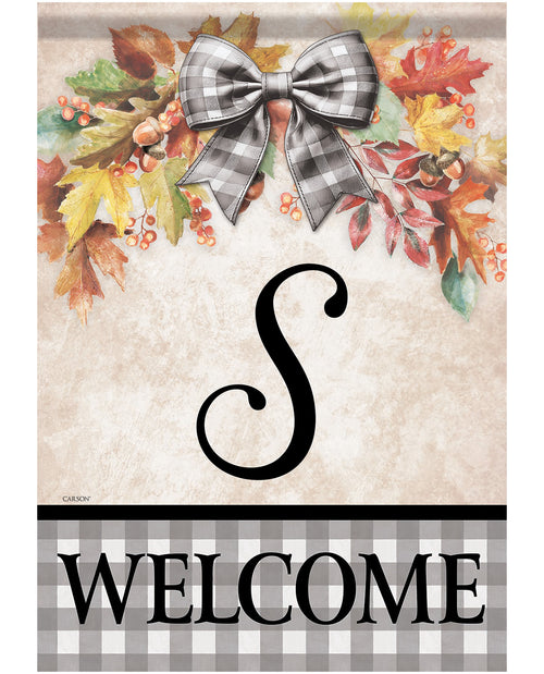 A decorative autumn-themed welcome sign with a faux-fur bow, colorful fall leaves, berries, and acorns at the top, a large black script letter S in the center, and the word WELCOME in black letters on a gray-and-white gingham band at the bottom.